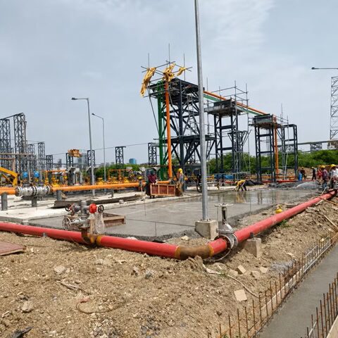 Civil construction work at an industrial plant site with utility piping, structural frames, and active groundwork.