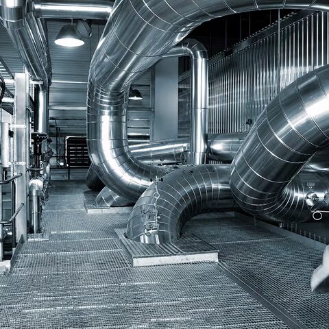 Industrial insulation and metal ductwork system installed inside a processing facility corridor.
